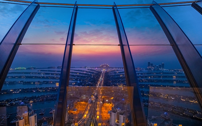 View from The Palm, Dubai at sunset, showcasing city lights and skyline.