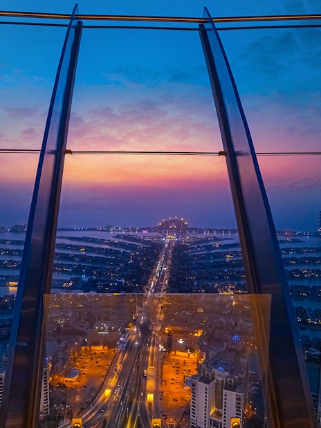 View from The Palm, Dubai at sunset, showcasing city lights and skyline.