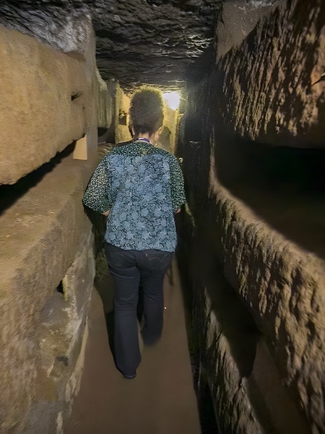 Person walking through narrow passage in Roman Catacombs during guided tour.