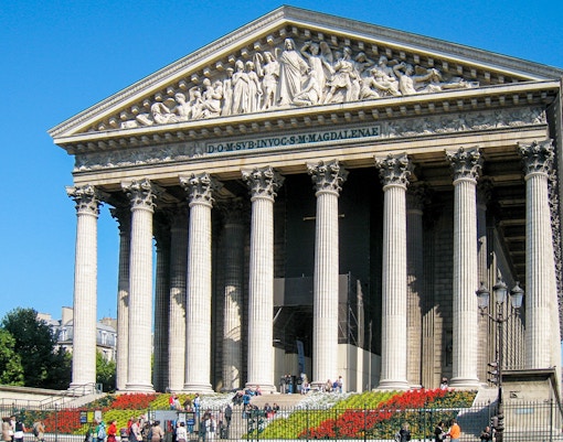 Place de la Madeleine in Paris with neoclassical columns and visitors.