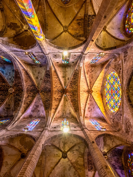 Ceiling view of Santa Maria de Majorica's gothic cathedral in Palma with stained glass windows.