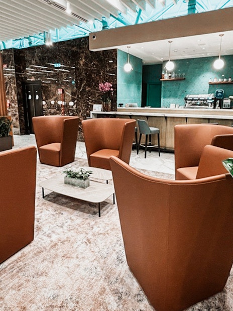 Premium lounge seating area at Rome Fiumicino Airport with modern decor and bar.