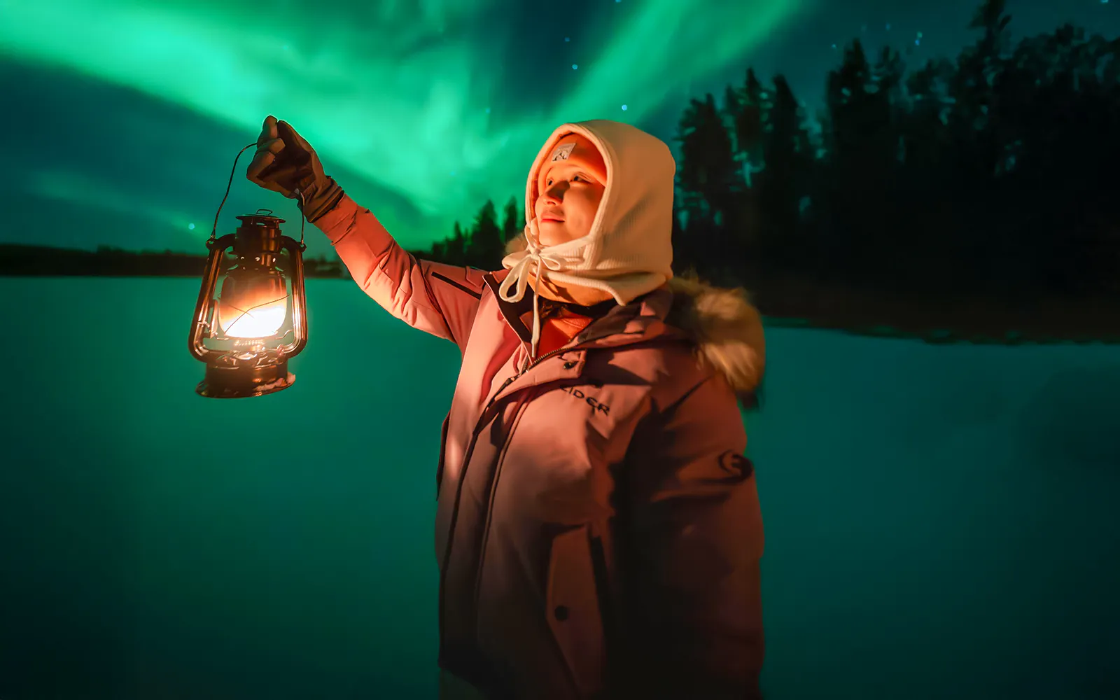 Guest holding lantern under Northern Lights on Rovaniemi bus tour.