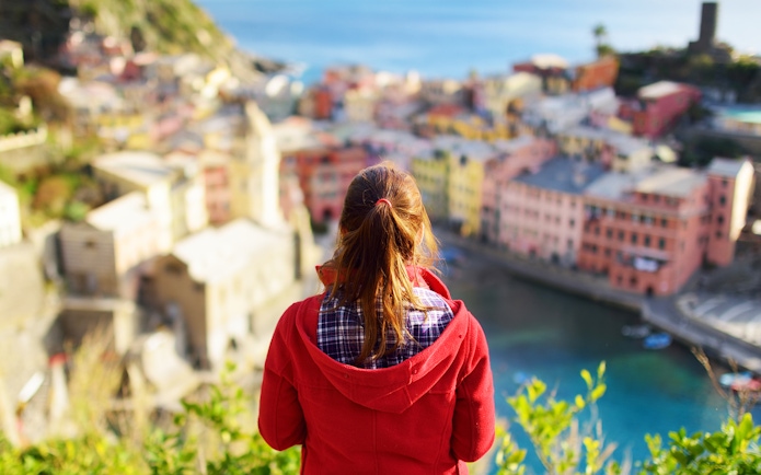 Person overlooking colorful buildings and coastline in Cinque Terre, Italy.