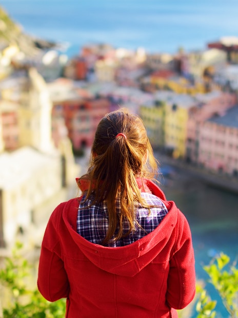 Person overlooking colorful buildings and coastline in Cinque Terre, Italy.