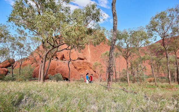 Walking tour at Uluru with visitors exploring the landscape during sunrise.