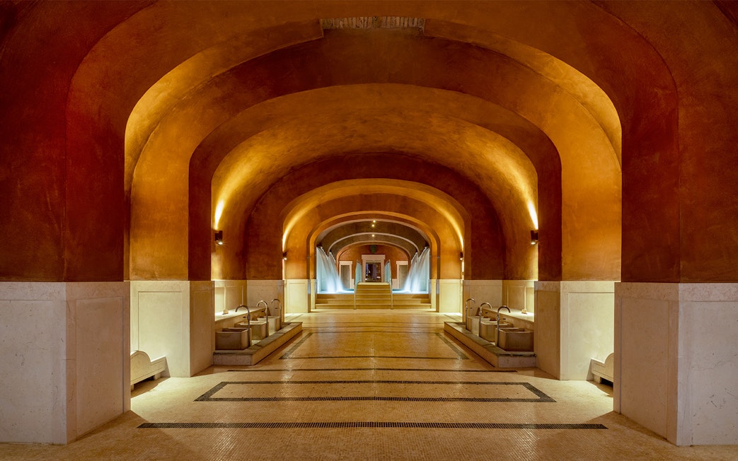 Spa interior with arched ceilings and fountains at QC Terme Roma, Italy.