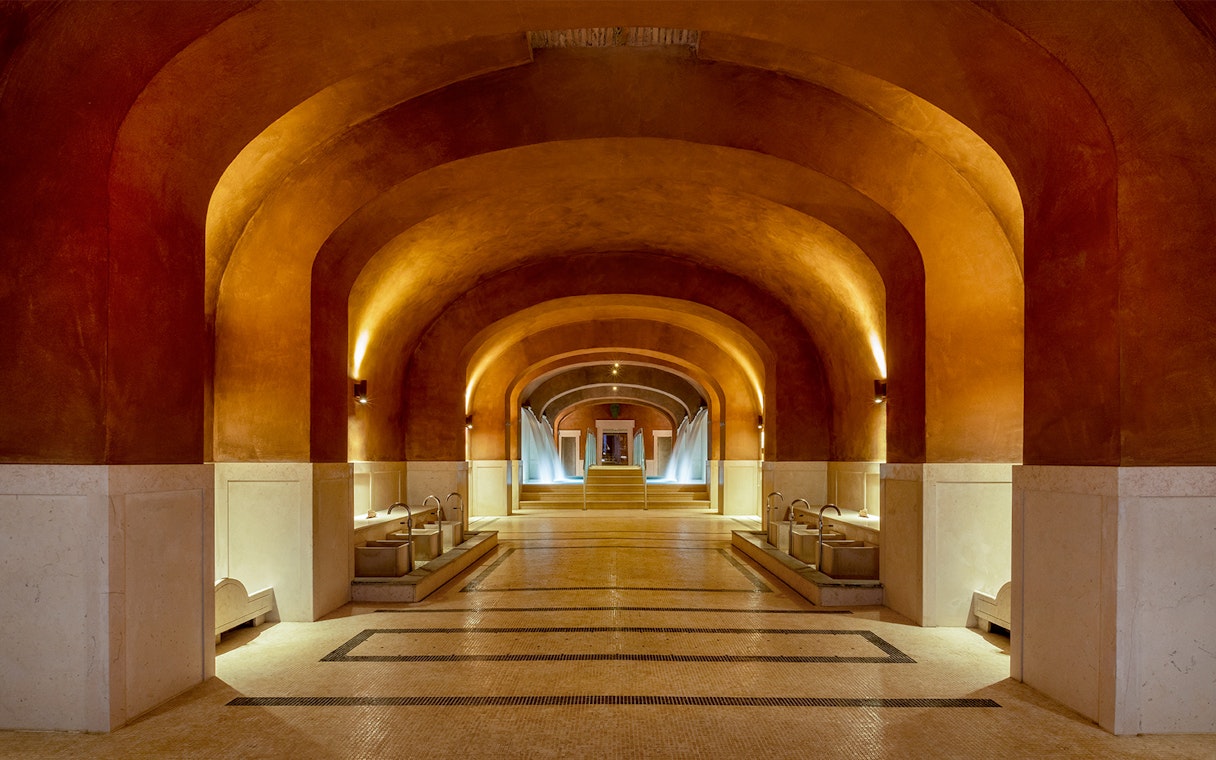 Spa interior with arched ceilings and fountains at QC Terme Roma, Italy.