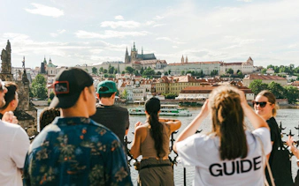 Tourists with guide overlooking Charles Bridge and Prague Castle in Prague.