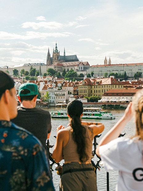 Tourists with guide overlooking Charles Bridge and Prague Castle in Prague.