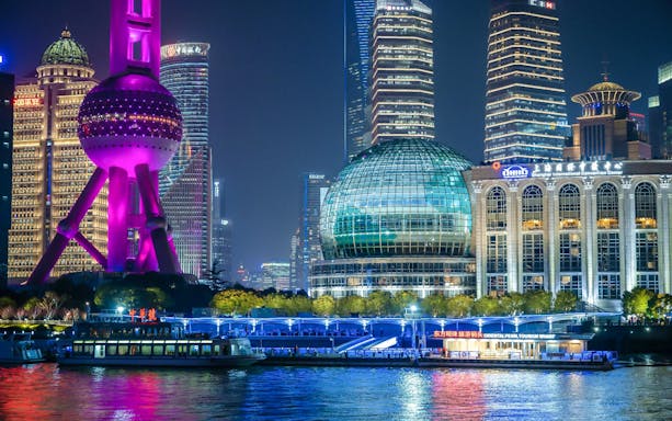Oriental Pearl Tower in Shanghai illuminated with purple lights at night.