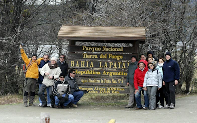 Group of tourists at Tierra del Fuego National Park entrance sign, Argentina.