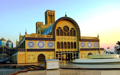 Sharjah Central Souq with intricate Arabic architecture and decorative tiles at sunset.
