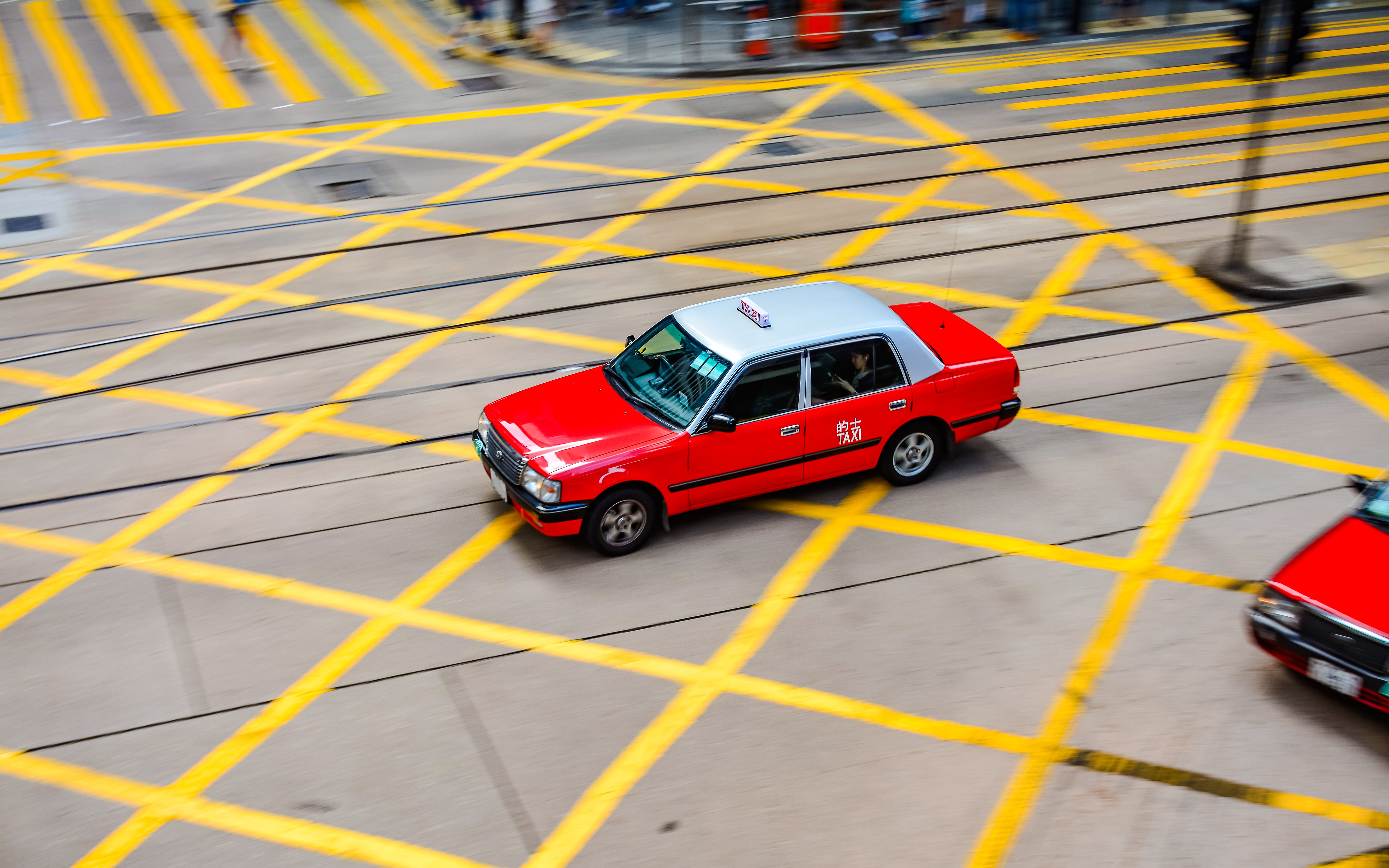 Red taxi driving through a busy intersection in Hong Kong.