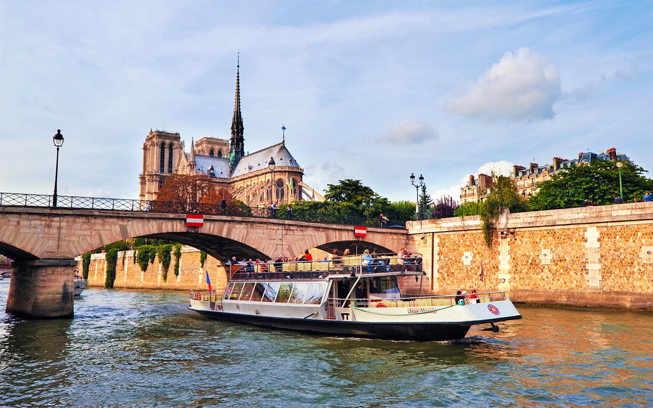 Seine River cruise boat passing Notre-Dame Cathedral in Paris.