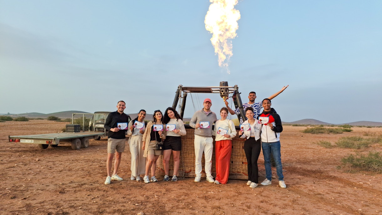 Tour group in Marrakech holding certificates after hot air balloon ride.