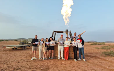 Tour group in Marrakech holding certificates after hot air balloon ride.