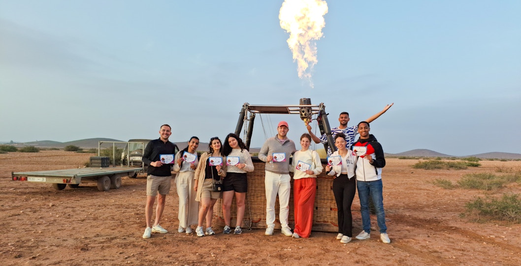Tour group in Marrakech holding certificates after hot air balloon ride.