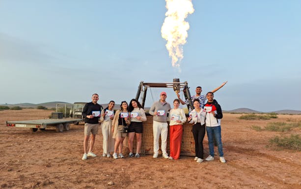 Tour group in Marrakech holding certificates after hot air balloon ride.