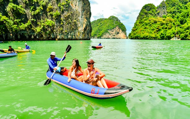 Tourists kayaking near limestone cliffs at James Bond Island, Phang Nga Bay, Thailand.