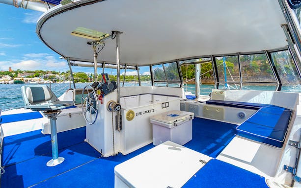 Interior of a boat on Sydney Harbour Cruise at sunset with seating and life jackets.
