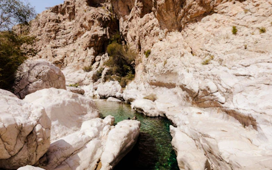 Wadi Bani Khalid's rocky landscape with clear water pools, part of Muscat's guided desert tour.