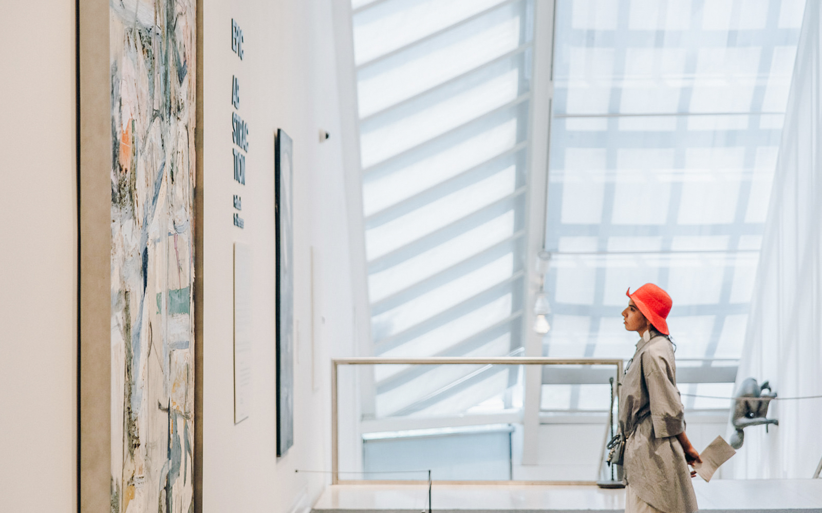 Person in grey coat and red hat viewing abstract art at the Metropolitan Museum of Art.
