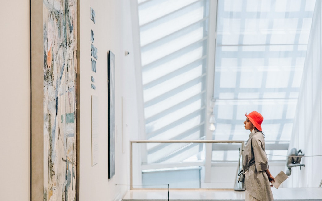 Person in grey coat and red hat viewing abstract art at the Metropolitan Museum of Art.