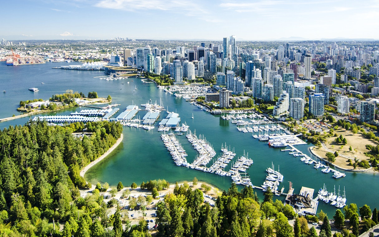 Aerial view of Stanley Park and Coal Harbour with Vancouver skyline in the background.