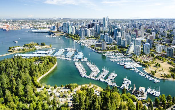 Aerial view of Stanley Park and Coal Harbour with Vancouver skyline in the background.