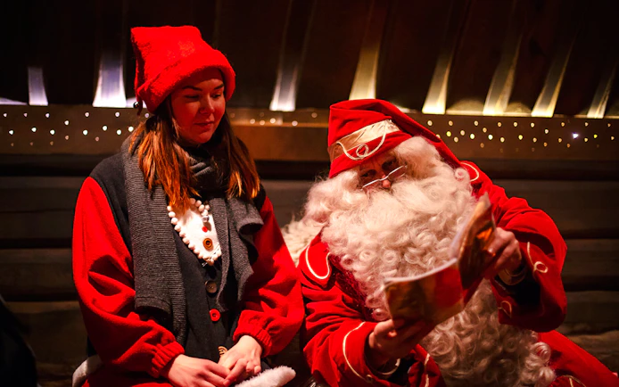 Santa Claus reading to a visitor at Santa Claus Village, Lapland.