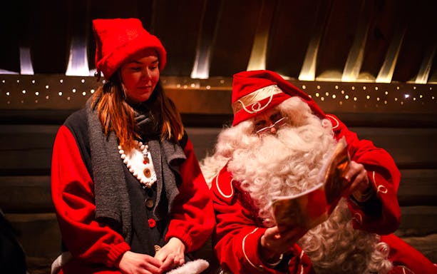 Santa Claus reading to a visitor at Santa Claus Village, Lapland.