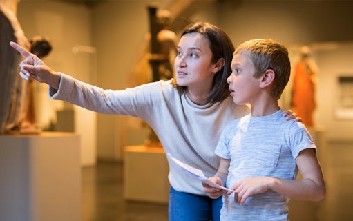 Woman guiding child through museum exhibit.
