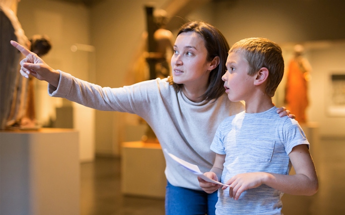 Woman guiding child through museum exhibit.