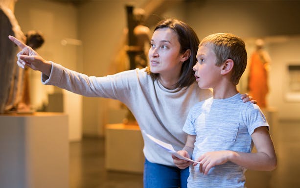 Woman guiding child through museum exhibit.
