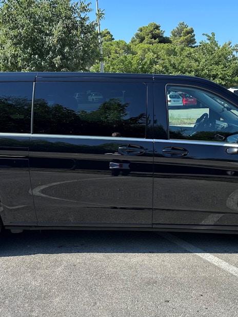 Mercedes E Class van side view in a parking lot with trees in the background.