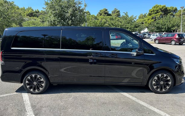 Mercedes E Class van side view in a parking lot with trees in the background.