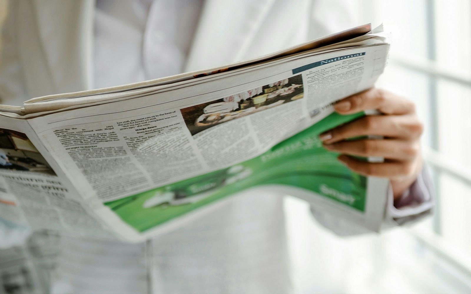 Man reading newspaper at a café in Paris, France.