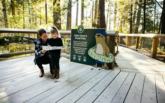 Mother and child exploring activity board at Capilano Suspension Bridge Park, Vancouver.