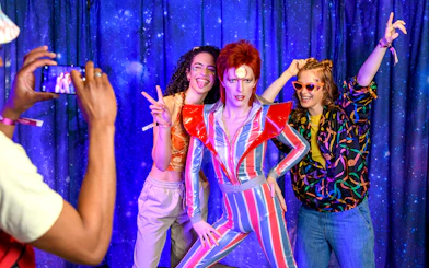 Visitors posing with a wax figure at Madame Tussauds, London.