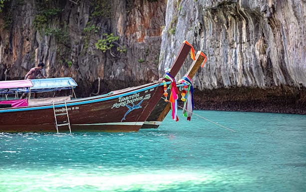 Longtail boat near limestone cliffs on a Phi Phi Islands charter from Phuket.