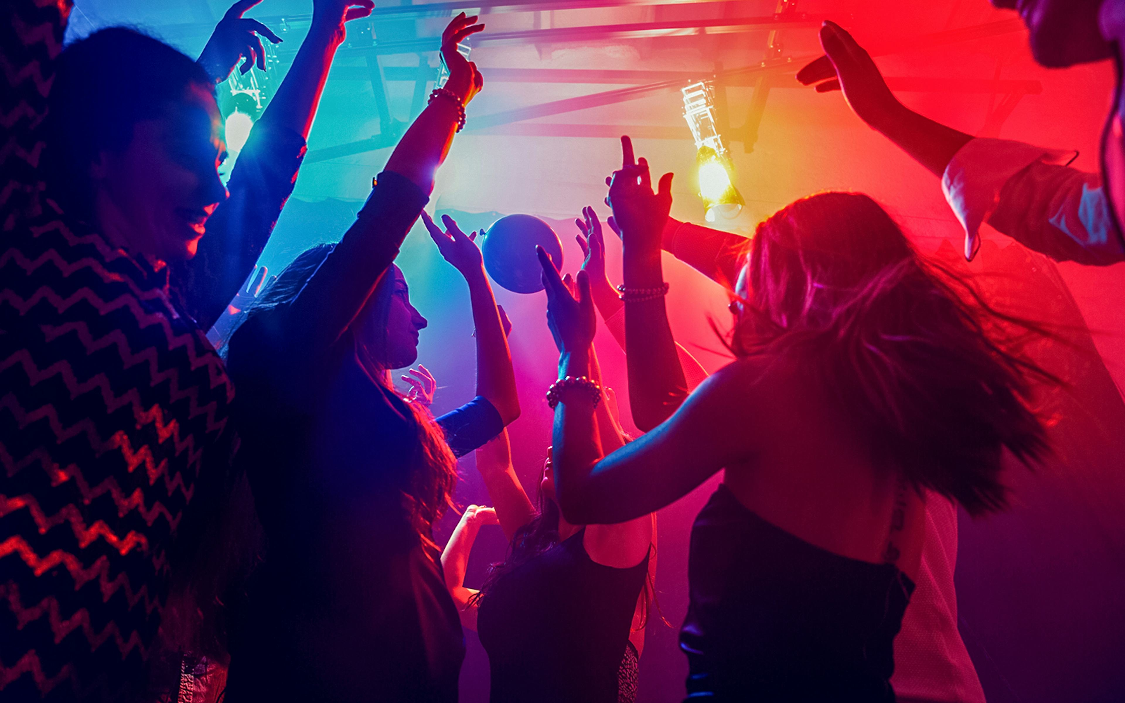 Friends dancing under colorful lights at a nightclub.