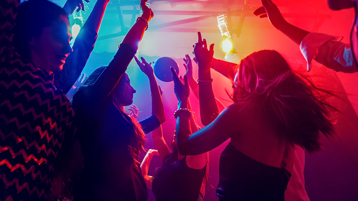 Friends dancing under colorful lights at a nightclub.