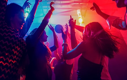 Friends dancing under colorful lights at a nightclub.