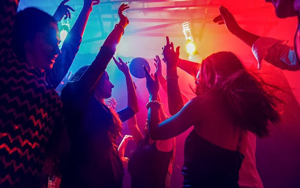 Friends dancing under colorful lights at a nightclub.