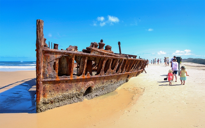 SS Maheno shipwreck on Fraser Island beach, K'gari, with tourists exploring.