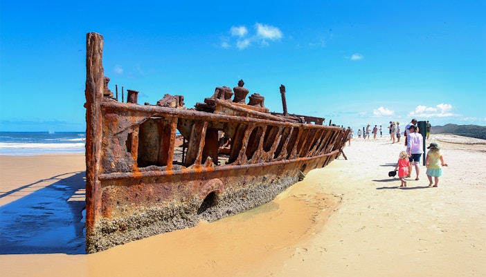 SS Maheno shipwreck on Fraser Island beach, K'gari, with tourists exploring.