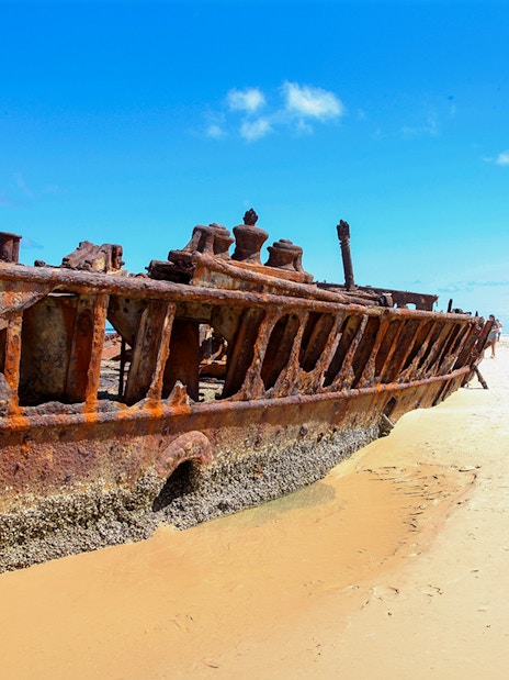 SS Maheno shipwreck on Fraser Island beach, K'gari, with tourists exploring.