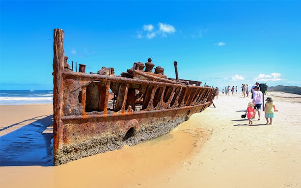 SS Maheno shipwreck on Fraser Island beach, K'gari, with tourists exploring.