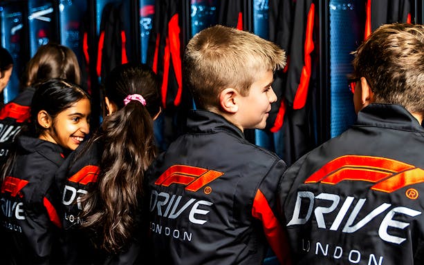 Children wearing F1® Drive London jackets in a locker room setting.